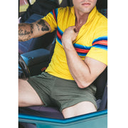 Man sitting in car wearing yellow polo and olive lounge shorts.