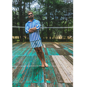 Man standing in tennis court  wearing blue and white stripped hoodie and shorts.