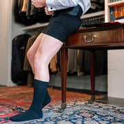 Man getting dressed in a suit wearing black slim fit boxers and black ribbed dress socks.