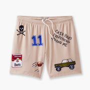 Beige lounge short that says "cash rules everything around me" with various icons like 11 patch, truck, football, skull and bones etc sitting flat with grey background. 