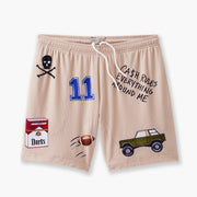 Beige lounge short that says "cash rules everything around me" with various icons like 11 patch, truck, football, skull and bones etc sitting flat with grey background.