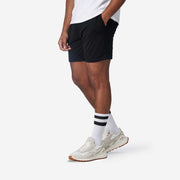 Side view shot of man wearing black lounge short with hand in pocket.