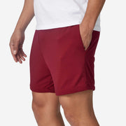 Close up side view of mean wearing burgundy lounge short with hand in pocket.