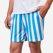 Close up front shot of man wearing blue and white striped mesh shorts with hand in pocket.
