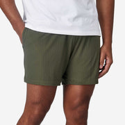 4" Matte Olive Pocket Lounge Short on model front tight crop on grey background.