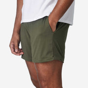 Side view of mean wearing olive lounge short with hand in pocket.