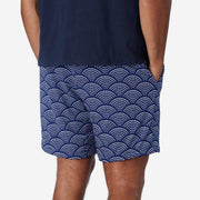 Back view of man wearing blue lounge shorts with sunrise pattern.