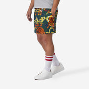 Side view of man wearing green lounge shorts with tiger and snake print with his hand in his pocket.