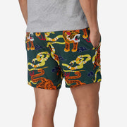 Back view of man wearing green lounge shorts with tiger and snake print with his hand in his pocket.