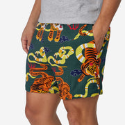 Man wearing green lounge shorts with tiger and snake print with his hand in his pocket.