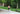 Shirtless man walking in forest with canoe and cabin in background wearing black lounge shorts.