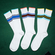 3 pairs of white Amalfi Athletic socks with stripes on the cuff in various colors sitting on green felt poker table