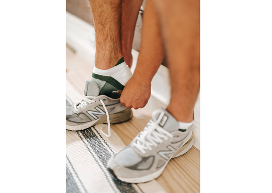 Close up of man putting on shoe wearing black/white performance ankle sock.