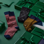 Monogram socks laid out next to green gift boxes on green background.