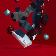 Monogram socks floating with NL gift boxes and red background.