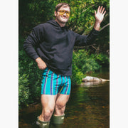 Man standing in water wearing boxers and a black hoodie
