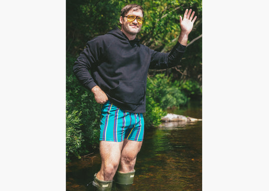 Man standing in water wearing boxers and a black hoodie