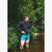 Man standing in water wearing boxers and a black hoodie