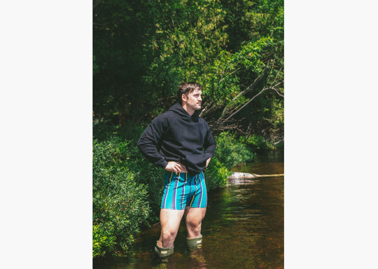 Man standing in water wearing boxers and a black hoodie