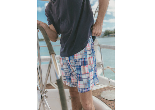 Close up of man on boat wearing dark navy blue shirt and blue plaid print madras lounge short