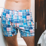 Shirtless man standing in boat bathroom wearing Blue Madras slim fit boxer.