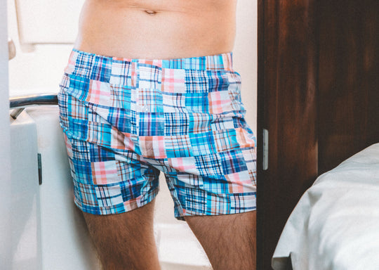 Shirtless man standing in boat bathroom wearing Blue Madras slim fit boxer.