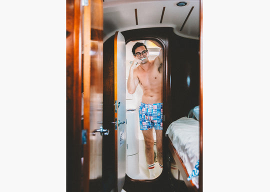 Shirtless man brushing teeth in boat bathroom wearing Blue Madras Slim Fit Boxers