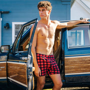 Shirtless man standing in front of a wagoneer wearing red/black buffalo plaid slim fit boxers.