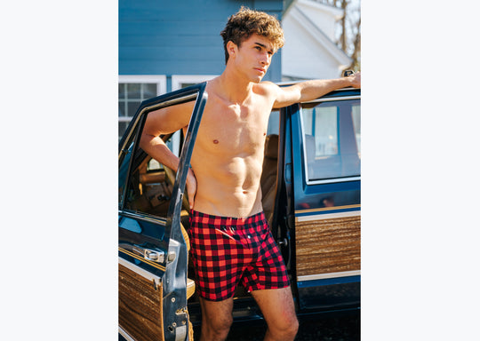 Shirtless man standing in front of a wagoneer wearing red/black buffalo plaid slim fit boxers.