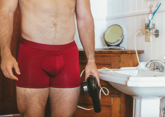 Close up shot of shirtless man in bathroom wearing burgundy boxer briefs