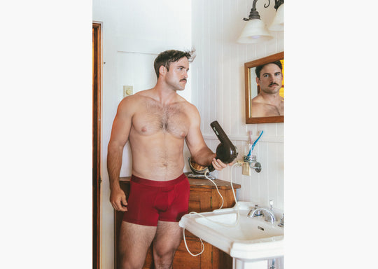 shot of shirtless man in bathroom wearing burgundy boxer briefs