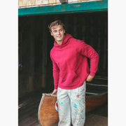 Close up of man in boathouse next to canoe wearing burgundy hoodie