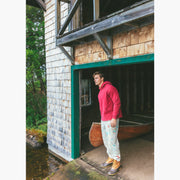 Man sitting in boathouse next to canoe wearing burgundy hoodie