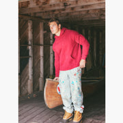 Man standing in boathouse next to canoe wearing burgundy hoodie