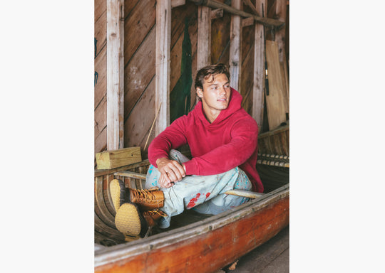 Man sitting in canoe wearing burgundy hoodie