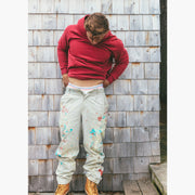 Man standing next to wooden wall wearing burgundy hoodie