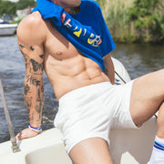 Man sitting on boat half shitless wearing cream lounge shorts.