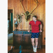 Man standing in house with wood walls wearing burgundy vintage ringer shirt