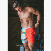Shirtless man in boathouse wearing Canoe Stripe lounge shorts.