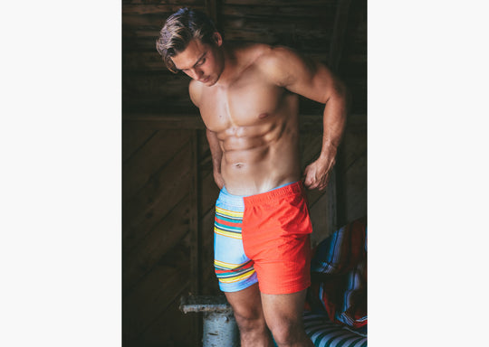 Shirtless man in boathouse wearing Canoe Stripe lounge shorts.