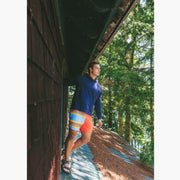Man wearing navy sweatshirt and Canoe stripe lounge short leaning out window on roof.