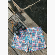 Pair of classic madras slim fit boxers sitting flat on boat dock next to binoculars 