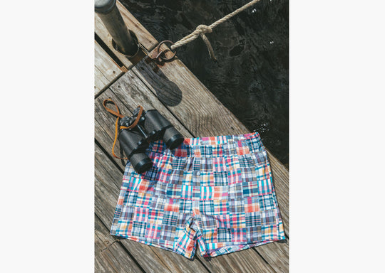Pair of classic madras slim fit boxers sitting flat on boat dock next to binoculars 