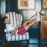 Man in chair in collegiate stripe slim fit boxers and tech varsity socks.