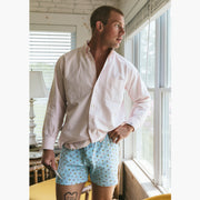 Man standing inside wearing white dress shirt and Light Blue Doghouse slim fit boxer (orange with small icons like dog house, golf clubs, card etc)