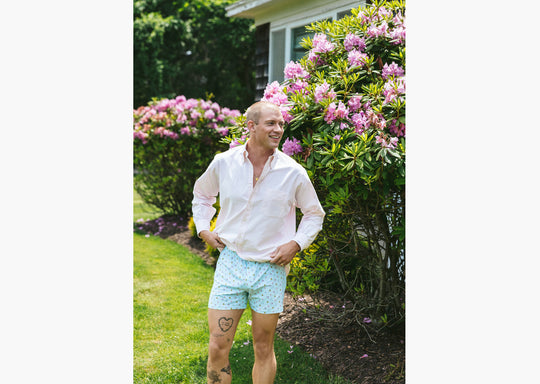 Man standing outside wearing white dress shirt and Light Blue Doghouse slim fit boxer (orange with small icons like dog house, golf clubs, card etc)