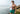 Shirtless man standing outside by ocean shaving wearing a green Doghouse slim fit boxer (green  with small icons like dog house, golf clubs, card etc)