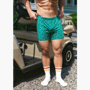 Close up short of shirtless man standing in front of a golf cart wearing a green Doghouse slim fit boxer (green  with small icons like dog house, golf clubs, card etc)