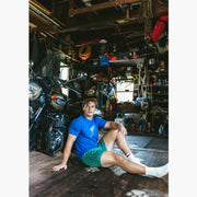 Man sitting in front of motorcycle in garage wearing a green Doghouse slim fit boxer (green with small icons like dog house, golf clubs, card etc)