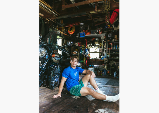 Man sitting in front of motorcycle in garage wearing a green Doghouse slim fit boxer (green with small icons like dog house, golf clubs, card etc)